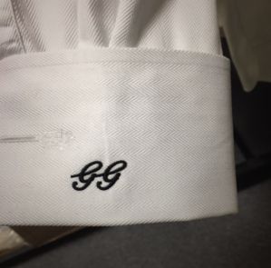 White shirt cuff with black embroidered GG initials.